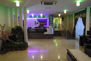 Um hall de hotel com balcão de recepção, escadaria e área de estar.