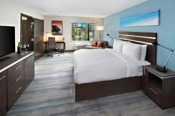 A hotel room with a bed, desk, chair, TV, and a window with a view.
