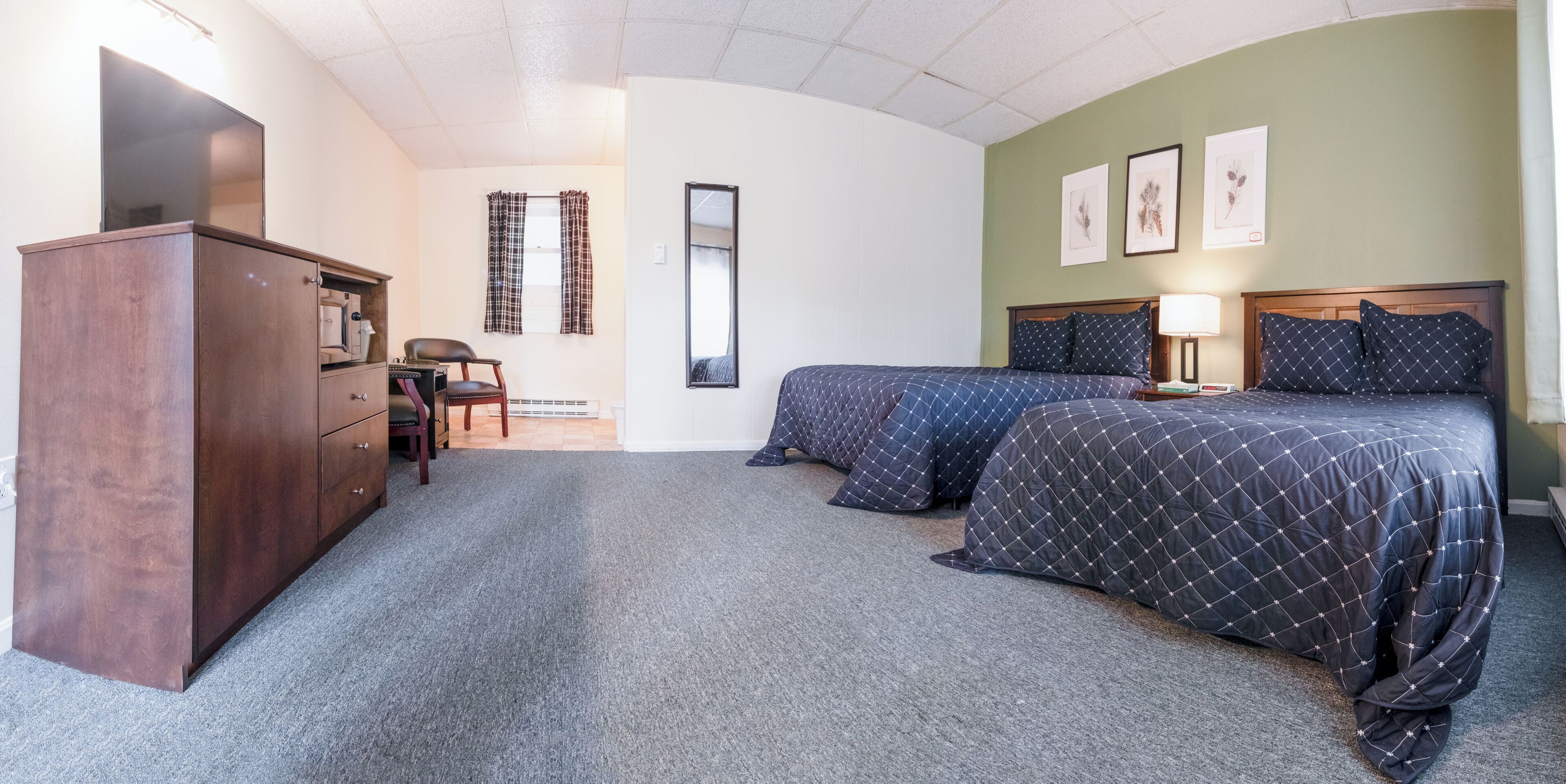 A bedroom with two beds, a dresser, a chair, a desk, and a mirror.