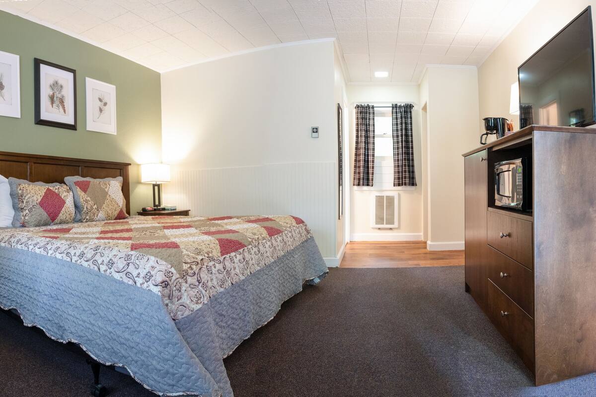 A bedroom with a bed, nightstands, a dresser, and a television.
