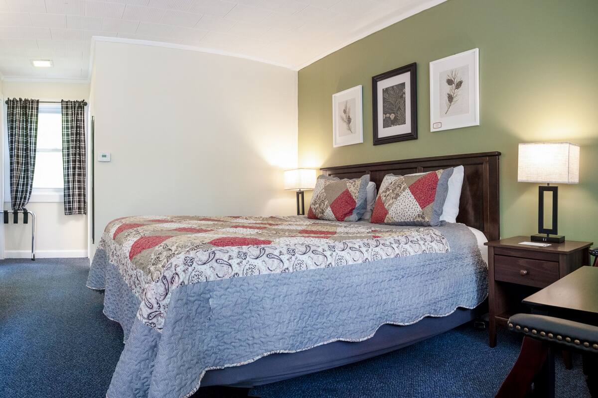 A neatly arranged bedroom with a bed, bedside tables, a desk, and a wardrobe.
