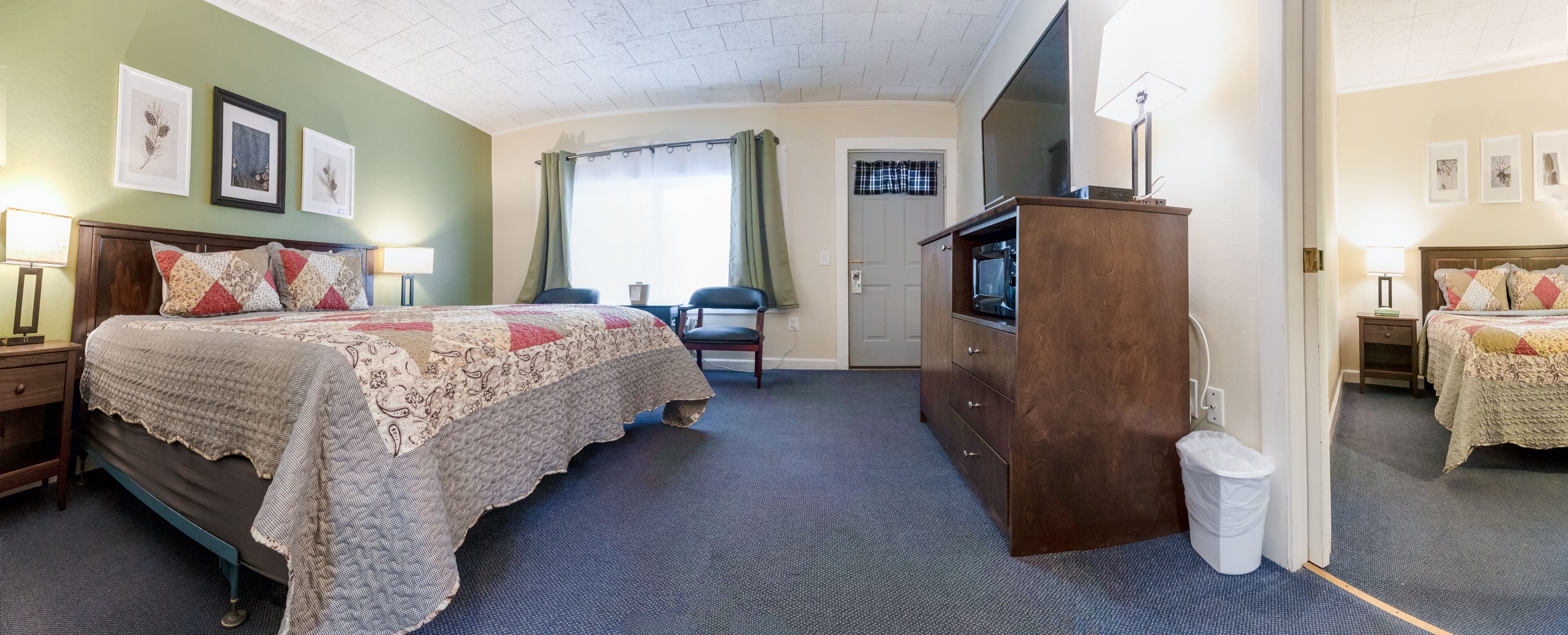 A hotel room with a bed, a desk, a chair, a television, and a wardrobe.