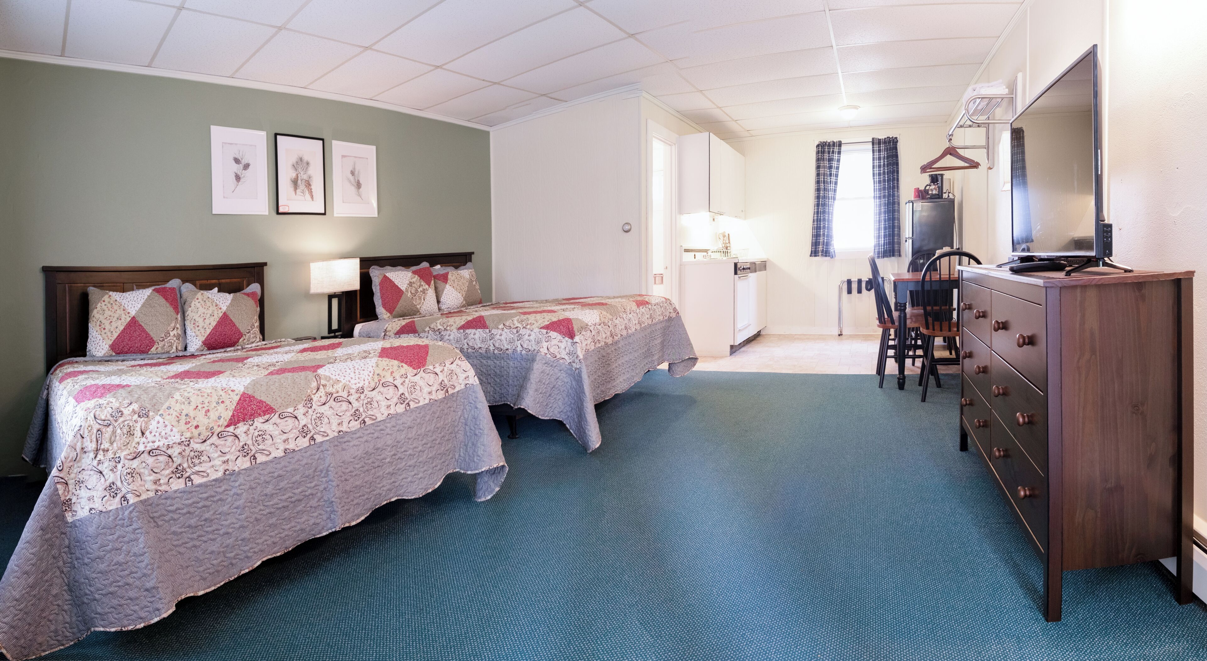 A hotel room with two beds, a dresser, a desk, and a chair.