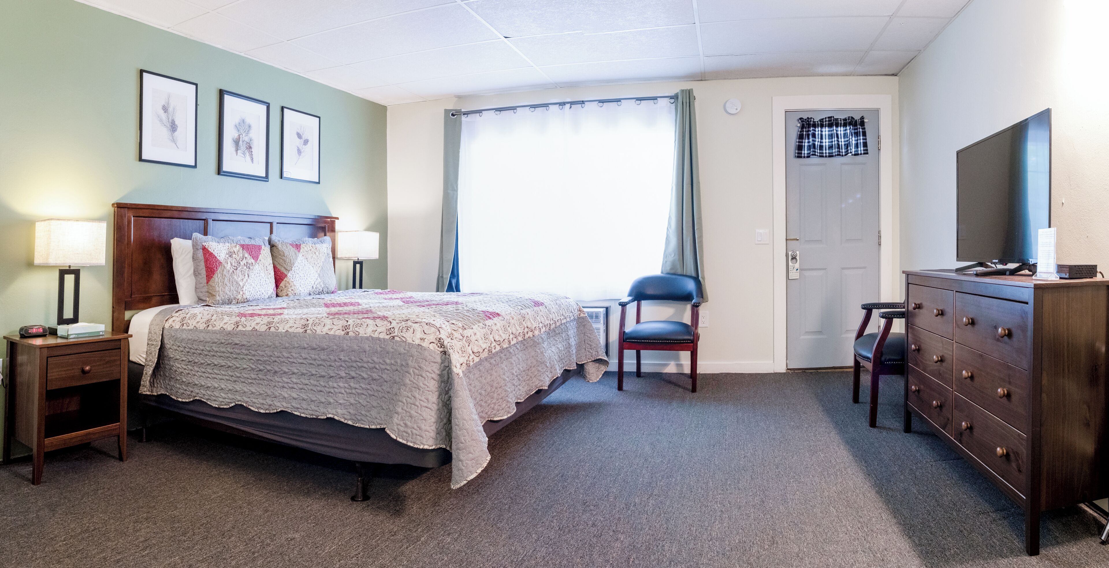 Une chambre à coucher comprenant un lit, des tables de chevet, une chaise, une commode et un téléviseur.