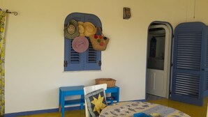 Una stanza con una porta blu, un tavolino con un cesto e una sedia con un cuscino a forma di stella.