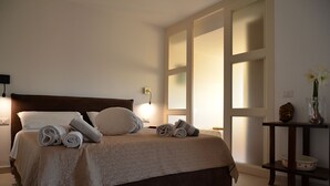 A neatly made bed with rolled towels, a wooden headboard, and a bedside table with a vase of flowers. - Bougainvillier
Villa in Pedra Longa. Panoramic view, private pool. (Porto Istana)