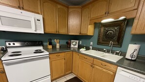 Une cuisine avec des meubles de rangement en bois, une cuisinière blanche, un évier et un four à micro-ondes.