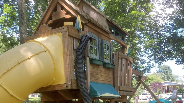 Une cabane en bois avec un toboggan jaune et un toit bleu.