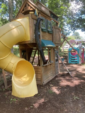 Une cabane en bois avec un toboggan jaune et un toit bleu.