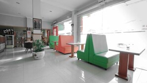 Un interior moderno con una zona de estar verde y naranja, una mesa blanca y una planta en maceta.