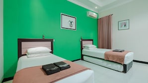 Habitación de hotel con dos camas, paredes verdes y una ventana con cortinas.