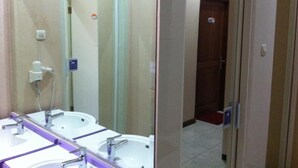 A bathroom with two sinks, a mirror, and a hairdryer. - The Cabin Hotel Sutomo (Yogyakarta)