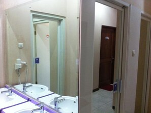 A bathroom with two sinks, a mirror, and a hairdryer. - The Cabin Hotel Sutomo (Yogyakarta)