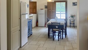 Uma cozinha com um arco, uma mesa de jantar com cadeiras e uma geladeira.
