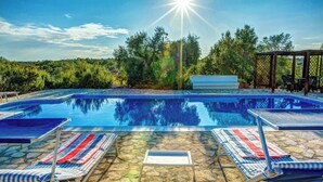 Piscina com espreguiçadeiras e área de estar coberta.