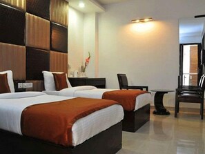 A hotel room with two beds, a desk, and a chair. - Delhi Pride (New Delhi)