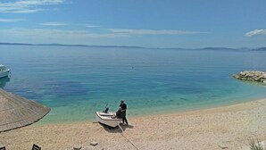Uma praia com um barco e uma pessoa ao lado dele.