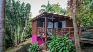Una cabana de fusta amb un balcó, envoltada de vegetació tropical.