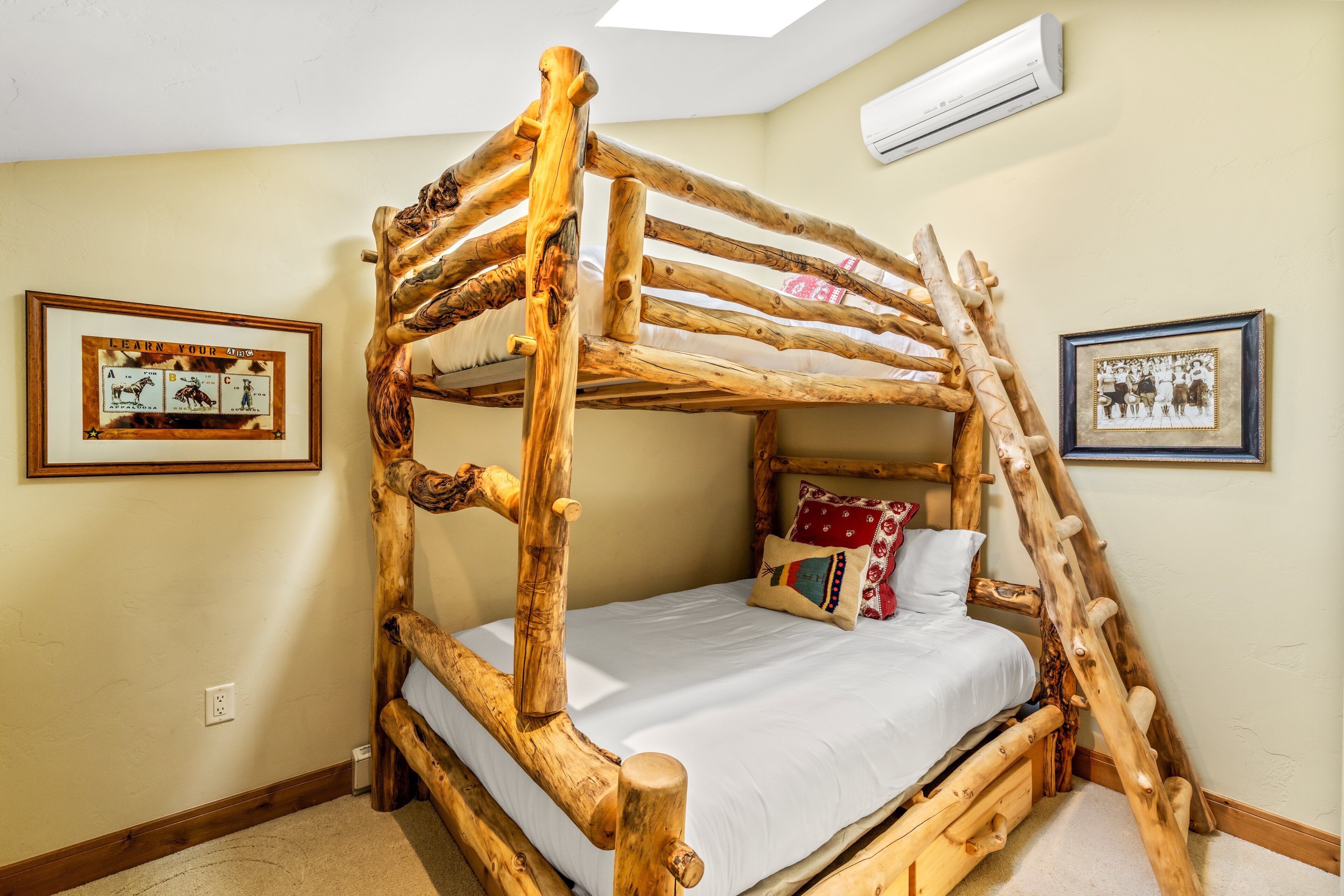 A bunk bed with a wooden frame, a white mattress, and a pillow with a colorful pattern.
