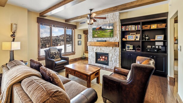 A cozy living room with a fireplace, leather furniture, and a stone accent wall. - Edgemont 2507 Luxury On Mountain Condo With Ski-In/Ski-Out Access! (Steamboat Springs)