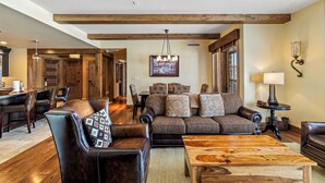 A spacious living room with a large sofa, a coffee table, and a dining area with chairs and a table. - Edgemont 2507 Luxury On Mountain Condo With Ski-In/Ski-Out Access! (Steamboat Springs)