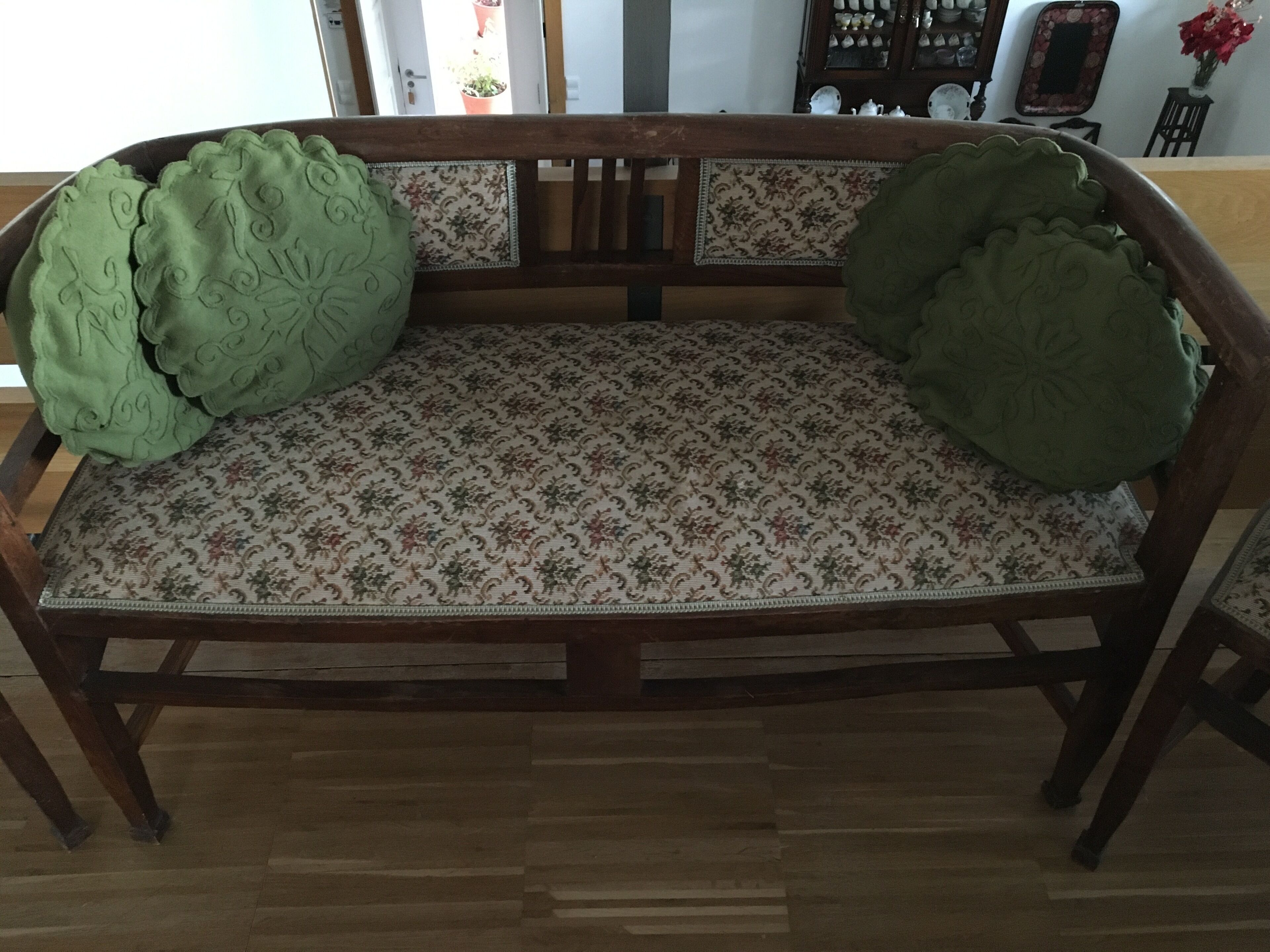 Un banc en bois avec un coussin à motifs et un coussin vert sur le dossier.