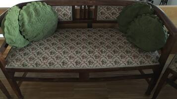 Un banc en bois avec un coussin à motifs et un coussin vert sur le dossier.