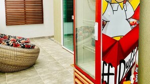 A Simpsons-themed refrigerator in a room with a wicker sofa and a window with blinds. - Wonderful house ❤️   (São Sebastião)