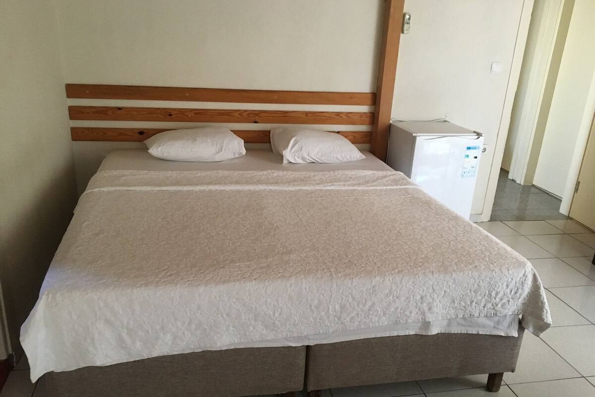 A bed with a wooden headboard, two pillows, and a white bedspread.