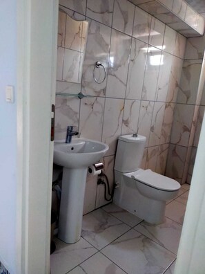 Ein Badezimmer mit Waschbecken, Toilette und Marmorfliesen.