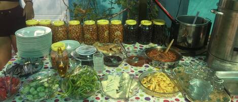 Una mesa de buffet con diversos alimentos, incluyendo frascos de pepinillos, una olla y recipientes con verduras.
