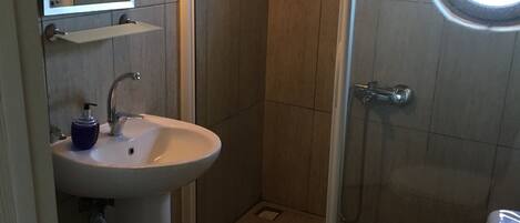 A bathroom with a sink, toilet, and a glass-enclosed shower.