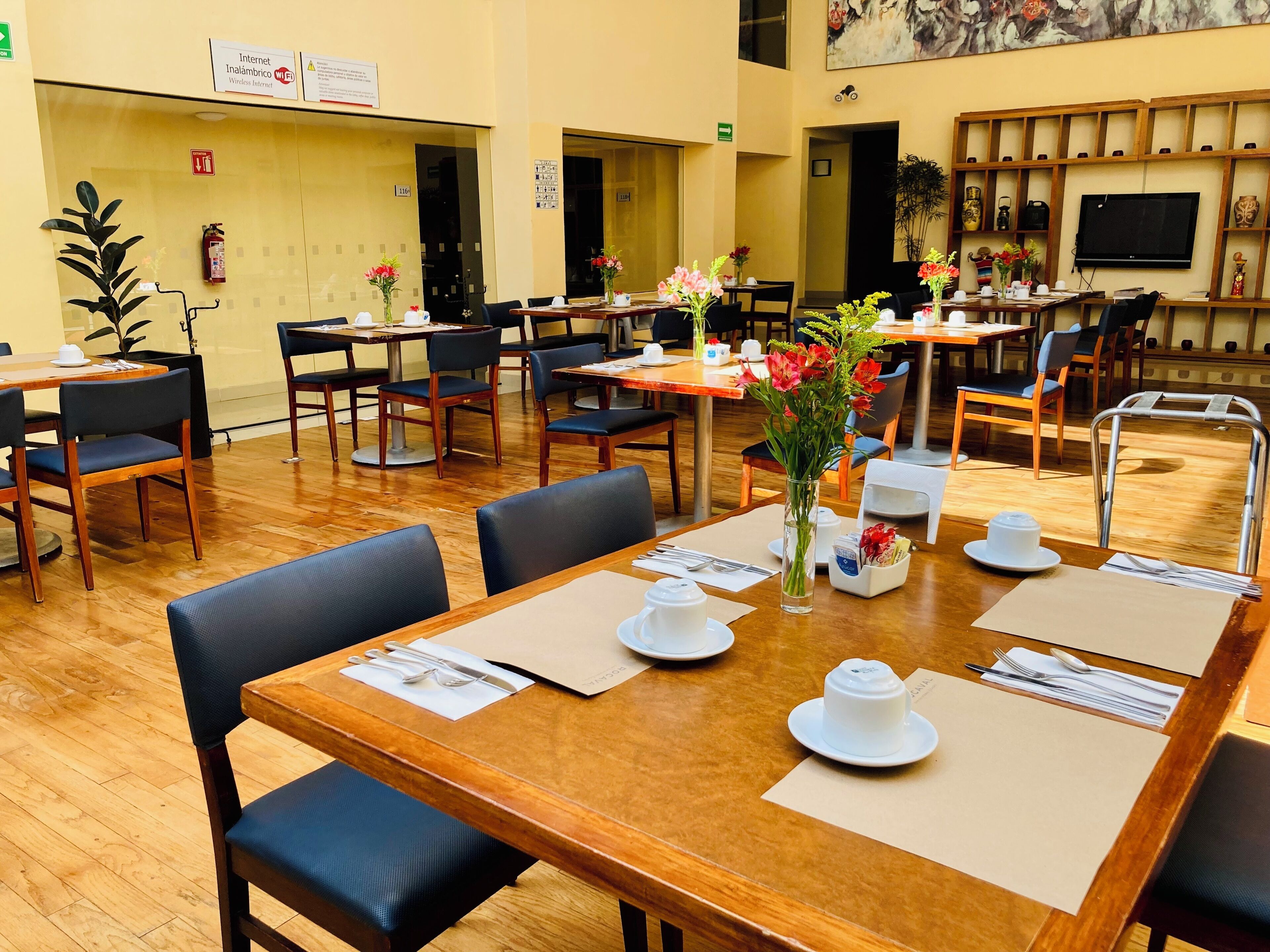 Un espace repas avec des tables et des chaises en bois, ainsi que des centres de table ornés de fleurs.