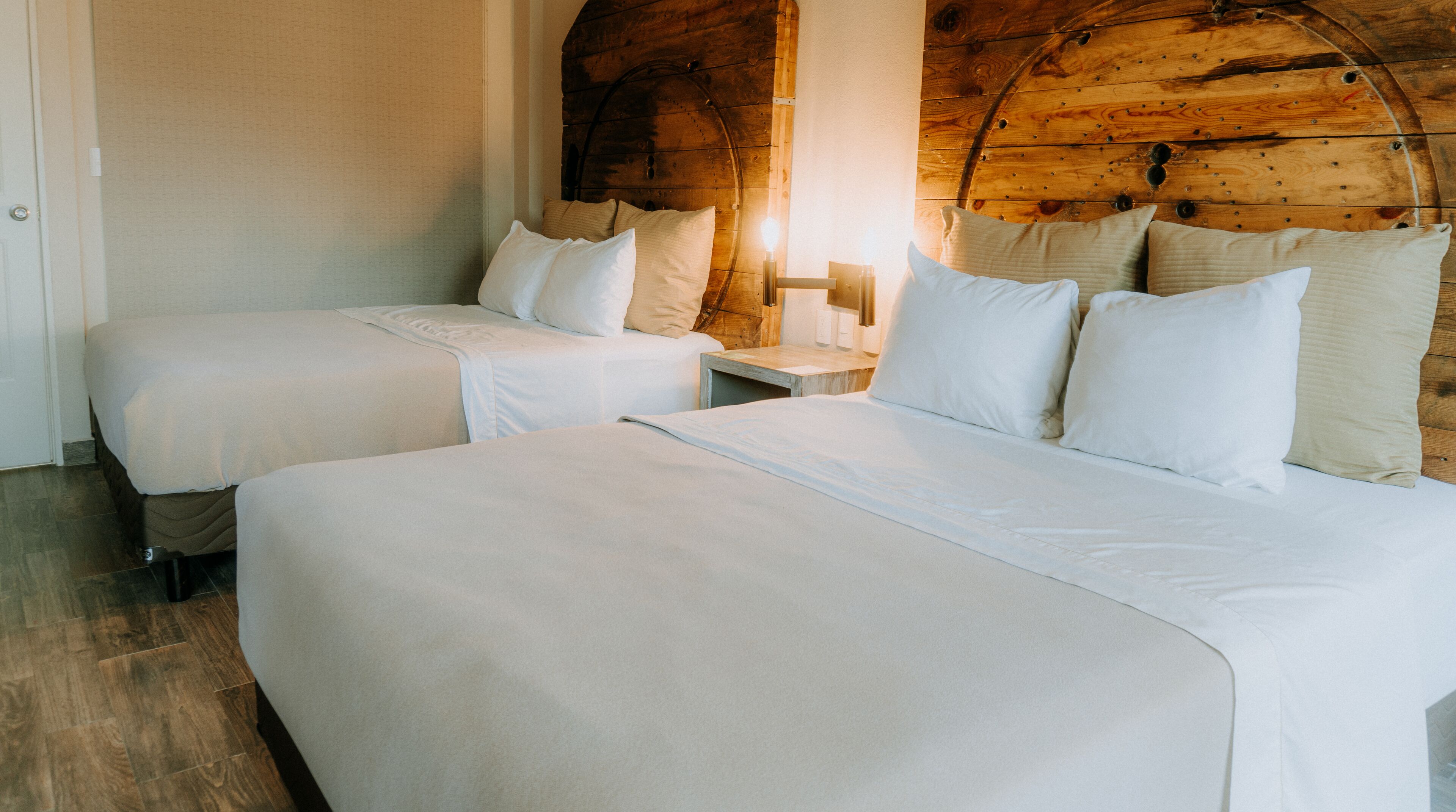 Une chambre d’hôtel avec deux lits, des poutres en bois au plafond et une table de chevet avec une lampe.