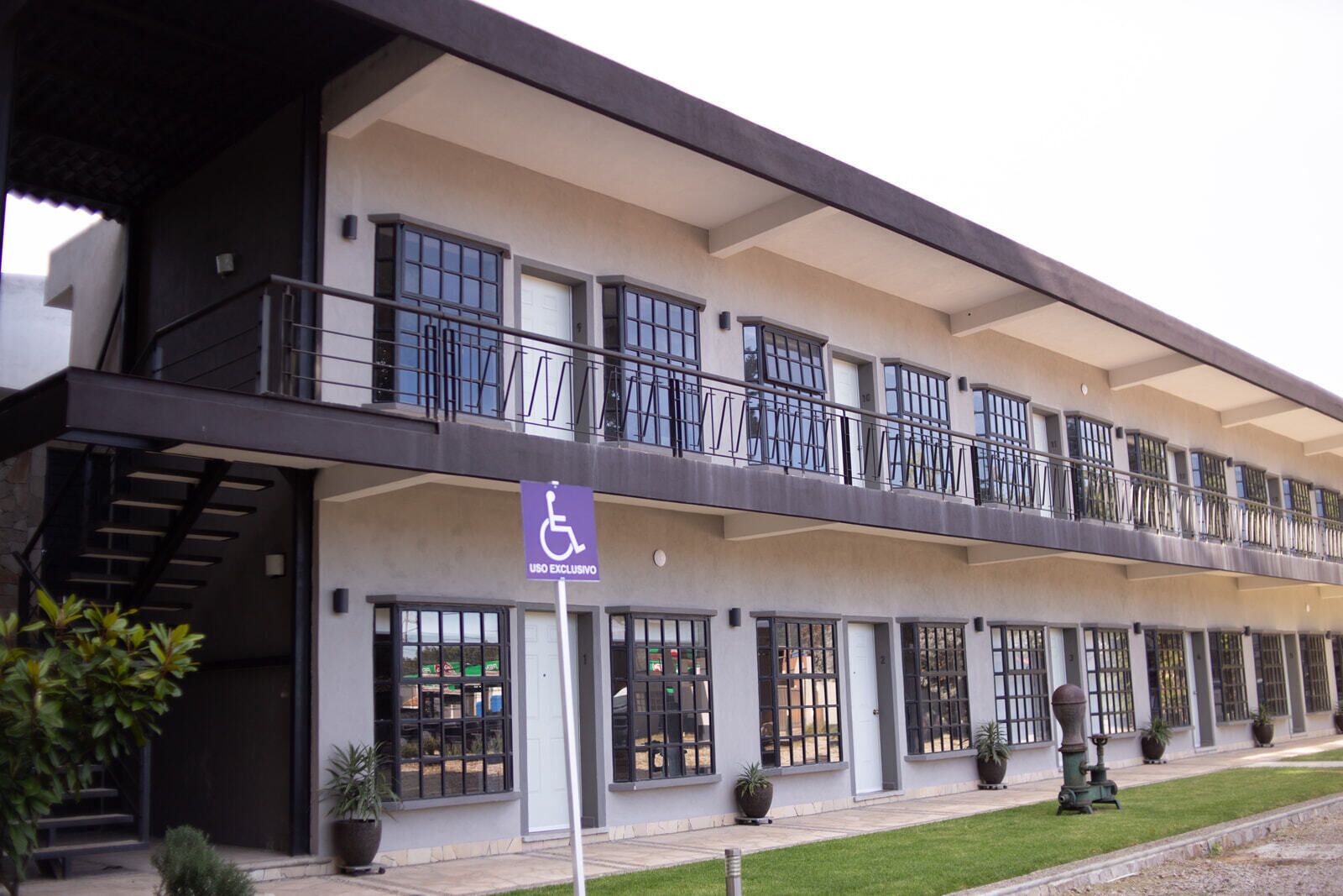 A multi-story building with a wheelchair-accessible entrance, large windows, and a balcony with railings.