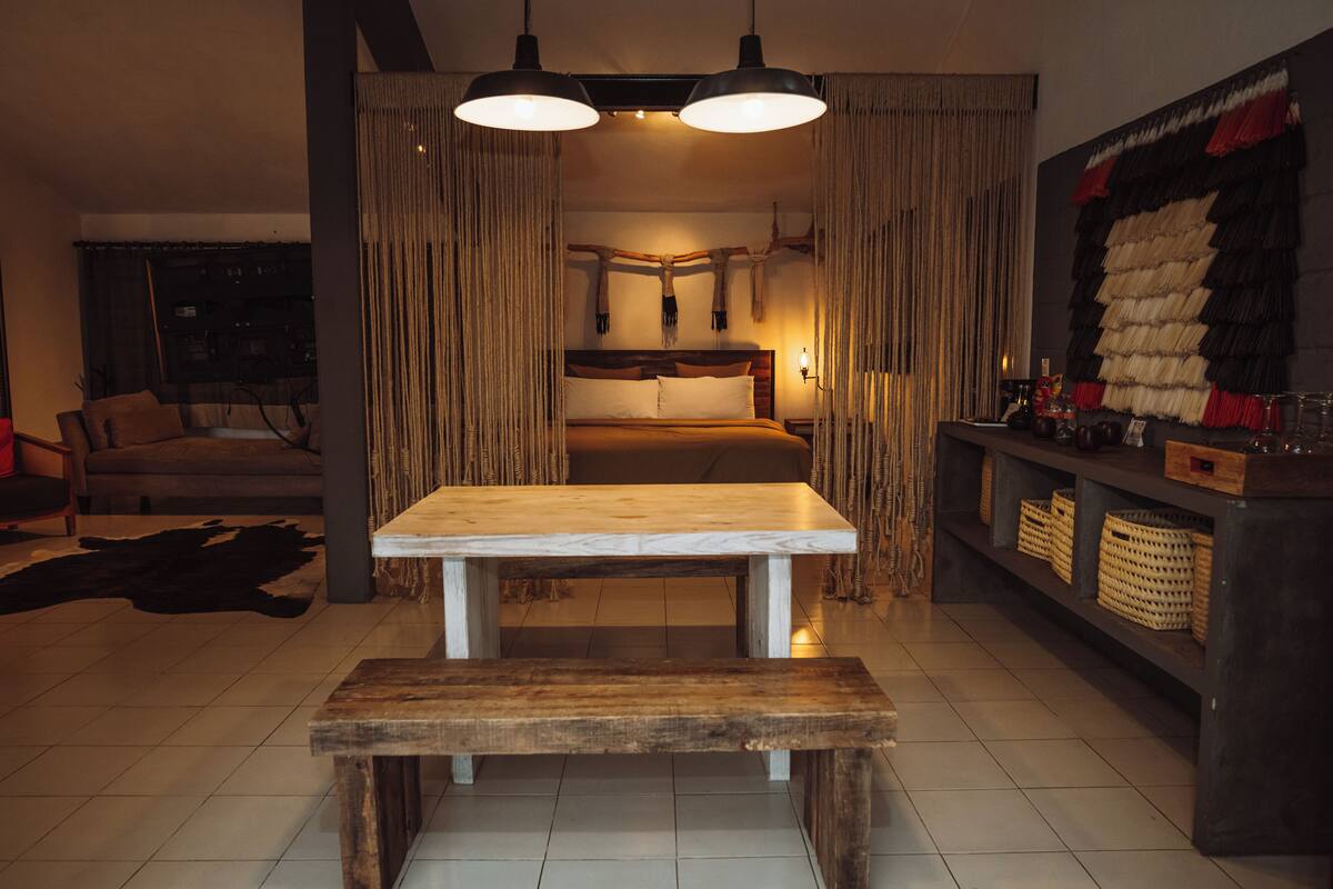 A cozy living room with a wooden bench, a sofa, and a dining table.