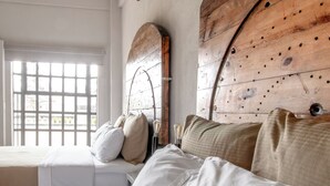 A bedroom with a large bed, a wooden headboard, and a window with blinds. - Hotel Rocaval (San Cristóbal de las Casas)