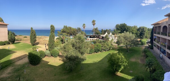 Un resort con piscina, abundante vegetación y vistas al mar.