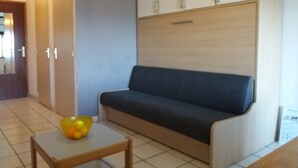 Un salon comprenant un canapé, une petite table avec un saladier et un meuble.