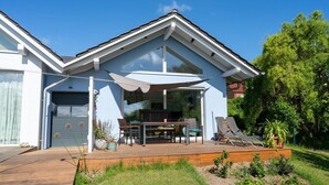Una casa moderna con una amplia terraza, un porche cubierto y un garaje.