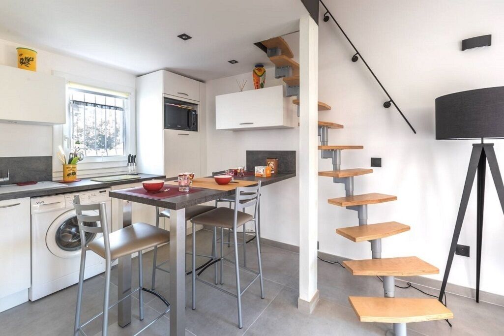Une cuisine moderne avec un coin repas, des appareils électroménagers intégrés et un escalier au design minimaliste.