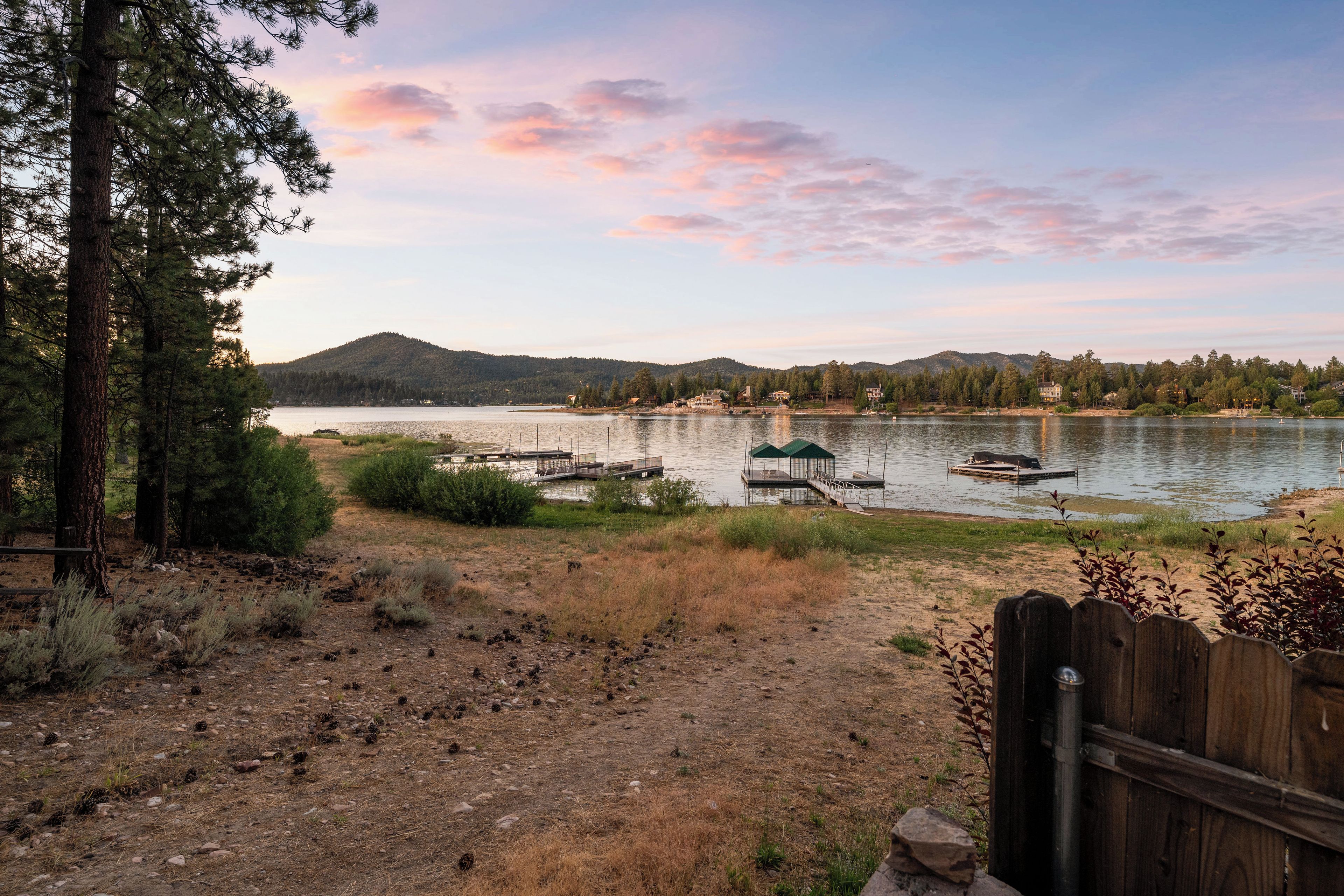 A lakeside view with docked boats, a wooden deck, and a mountain in the background.