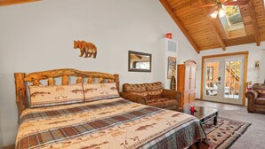 A cozy room with a large bed, a wooden headboard, a sofa, and a dining table.
