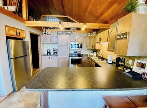 Une cuisine dotée de plans de travail en granit, d’appareils électroménagers en acier inoxydable et de meubles en bois.