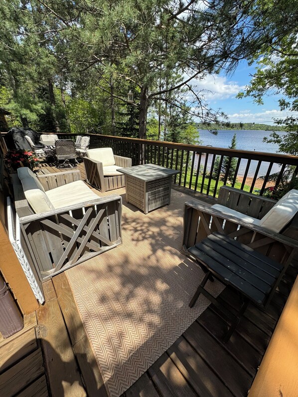 Una terraza con mobiliario exterior, un tapete con estampado de espiga y vistas a un lago.