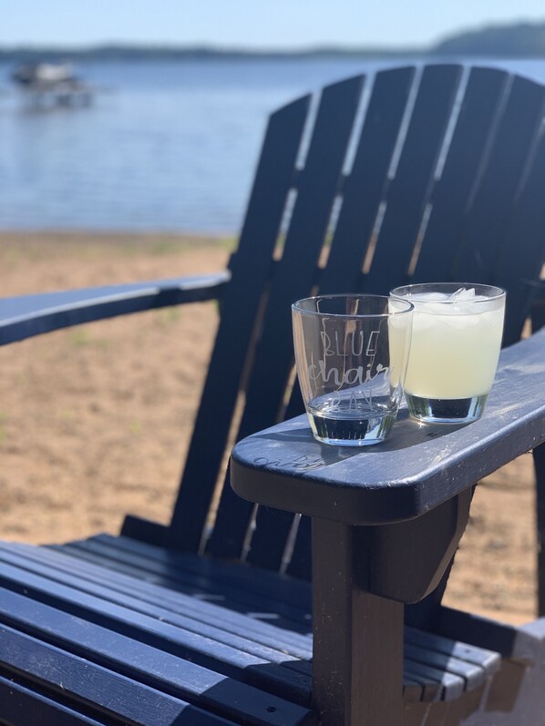 Een strandstoel met twee glaasjes drank op een tafel.