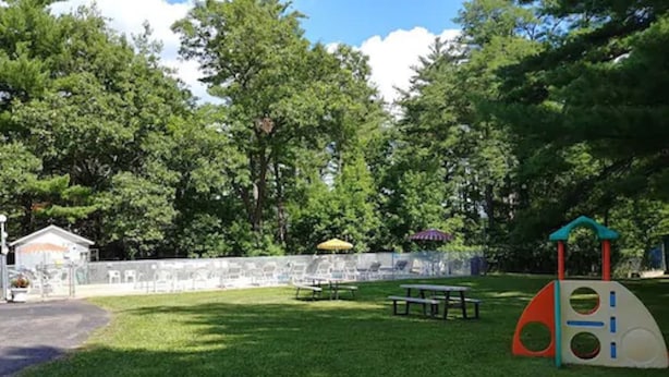 A park with picnic tables, a playground structure, and a stone wall. - Lake Aire Motel (Wisconsin Dells)