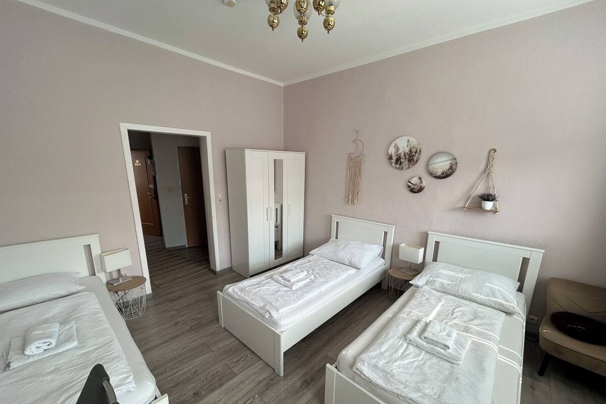 Une chambre d’hôtel avec deux lits simples, une armoire, une petite table et une chaise.