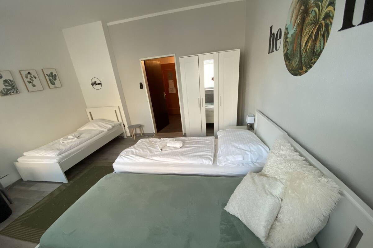 Une chambre d’hôtel avec un grand lit, un lit plus petit, un bureau et une chaise.
