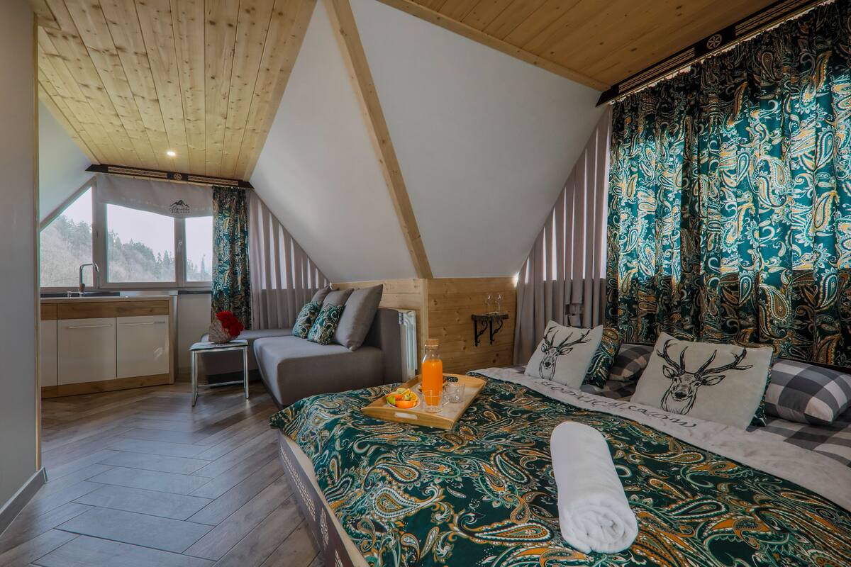 A bedroom with a bed, a bedside table, a window, and a view of the outdoors.